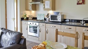 A kitchen with a dining table set for breakfast, including croissants, bread, and juice. - SWALLOWS COTTAGE - 24285 (Filey)