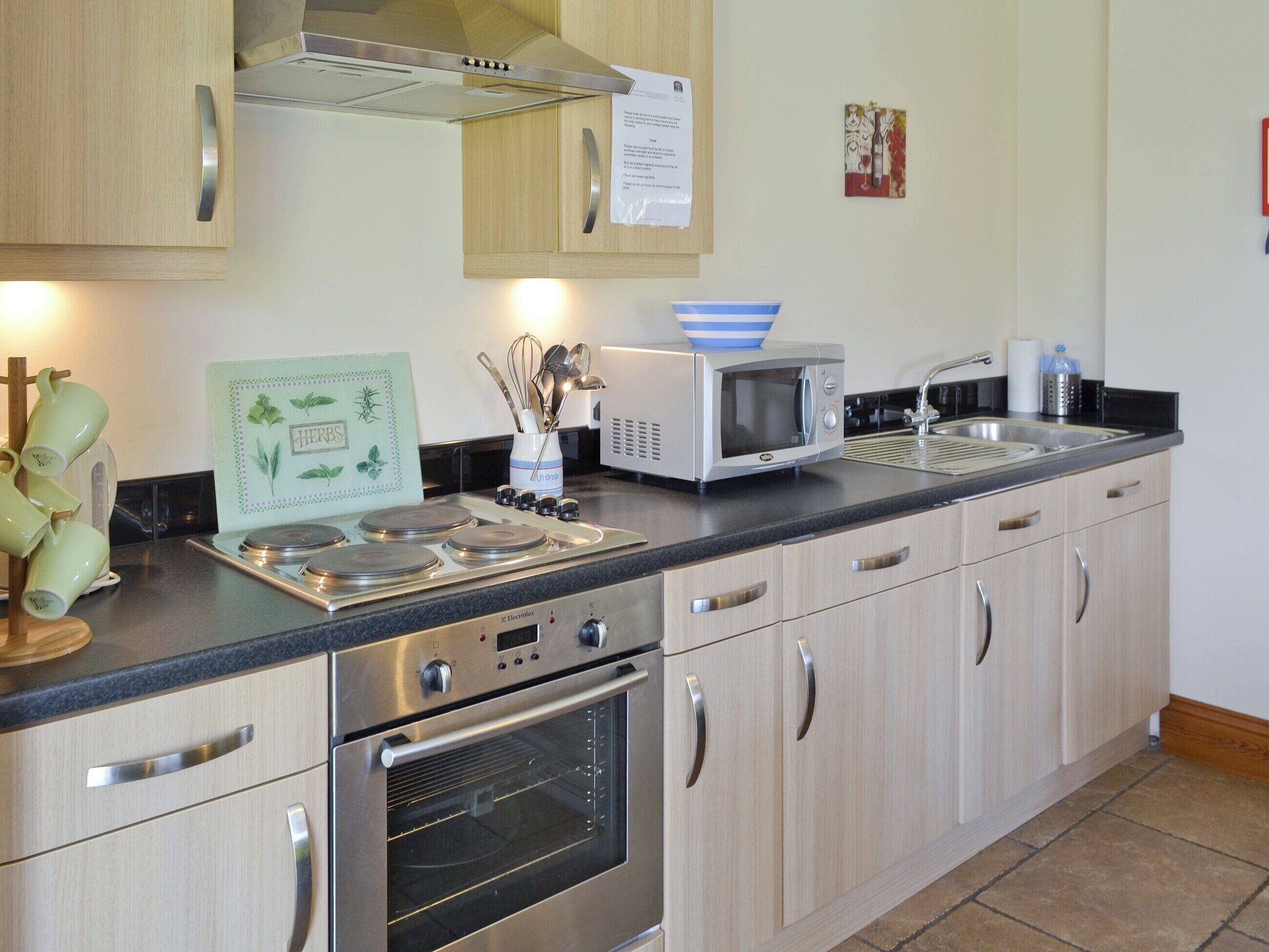 A modern kitchen with stainless steel appliances, wooden cabinets, and a tiled backsplash.