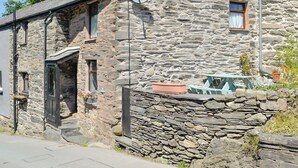 Un bâtiment en pierre à l’architecture traditionnelle, caractérisé par un mur en pierre, une porte et une petite fenêtre.