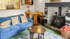 Un salon chaleureux avec un canapé bleu, une table basse ronde en bois et une cheminée en pierre.