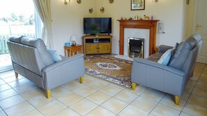 A living room with two grey sofas, a television, a fireplace, and a patterned rug. - 2 bedroom accommodation in Leiston, near Aldeburgh (Leiston, near Aldeburgh)