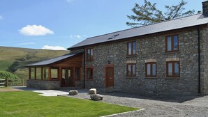 A stone building with multiple windows and a covered porch. - 3 bedroom accommodation in near Llanwrthwl, Powys (near Llanwrthwl, Powys)