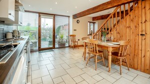 A spacious kitchen with a large dining table, wooden beams, and a sliding glass door leading to a garden. - 2 bedroom accommodation in Bream, near Lydney (Bream, near Lydney)