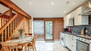 A modern kitchen with a wooden staircase, a dining area with a table and chairs, and a washing machine. - 2 bedroom accommodation in Bream, near Lydney (Bream, near Lydney)