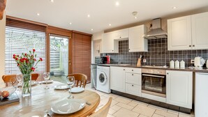 A modern kitchen with white cabinets, a built-in oven, and a dining area with a wooden table set for four. - 2 bedroom accommodation in Bream, near Lydney (Bream, near Lydney)