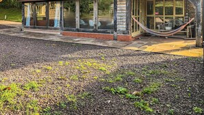 A house with a covered porch, a hammock, and a stone pathway leading to the entrance. - 3 bedroom accommodation in Waterrow, near Wiveliscombe (Waterrow, near Wiveliscombe)