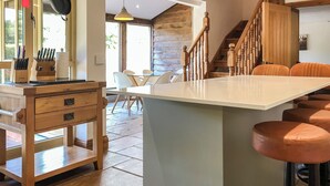 A kitchen with a central island, wooden stools, and a dining area with chairs. - 3 bedroom accommodation in Waterrow, near Wiveliscombe (Waterrow, near Wiveliscombe)