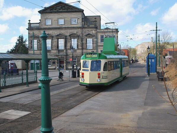 Un tramway dans une station, avec un bâtiment historique en arrière-plan.