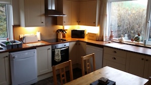 A compact kitchen with white cabinets, a microwave, a toaster, and a window with a view of trees. - Tigh Na Fraoch, (Skeabost)