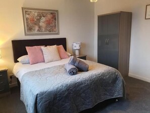A bedroom with a bed, nightstand, wardrobe, and a painting on the wall. - Tigh Na Fraoch, (Skeabost)