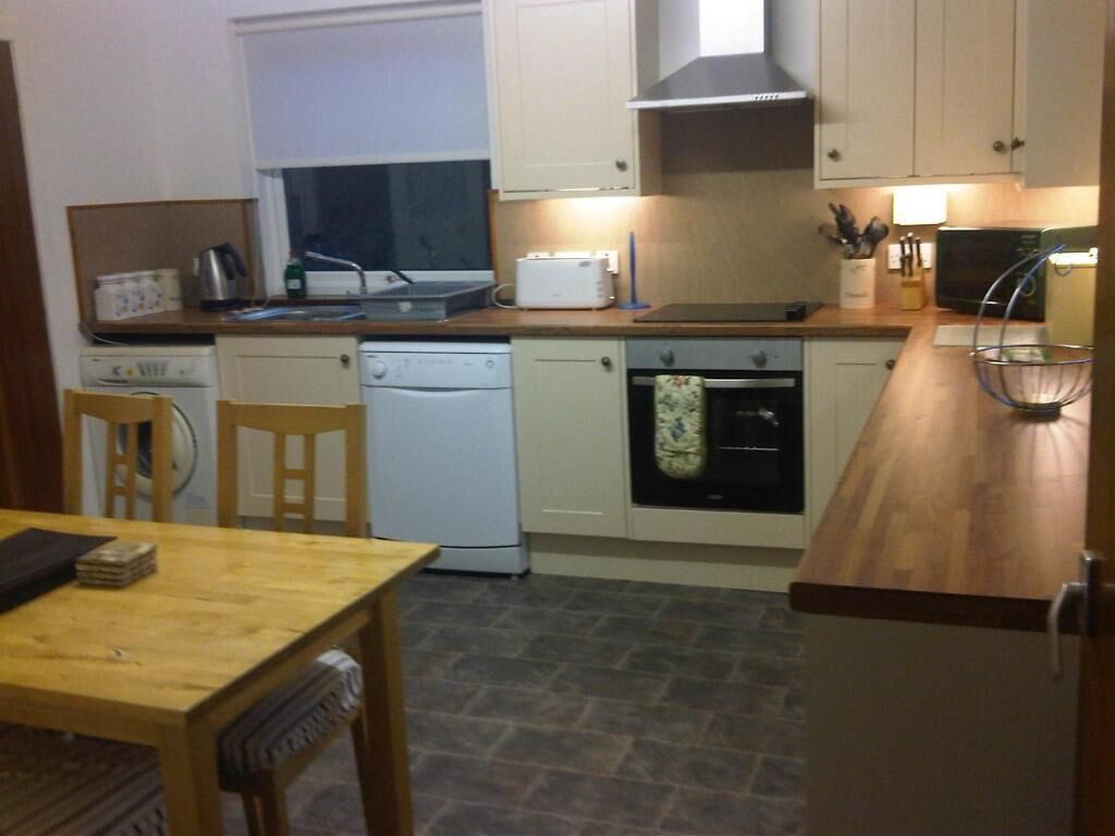 A compact kitchen with a dishwasher, oven, and a microwave on the countertop.