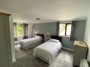 Une chambre avec deux lits simples, un bureau et une chaise.