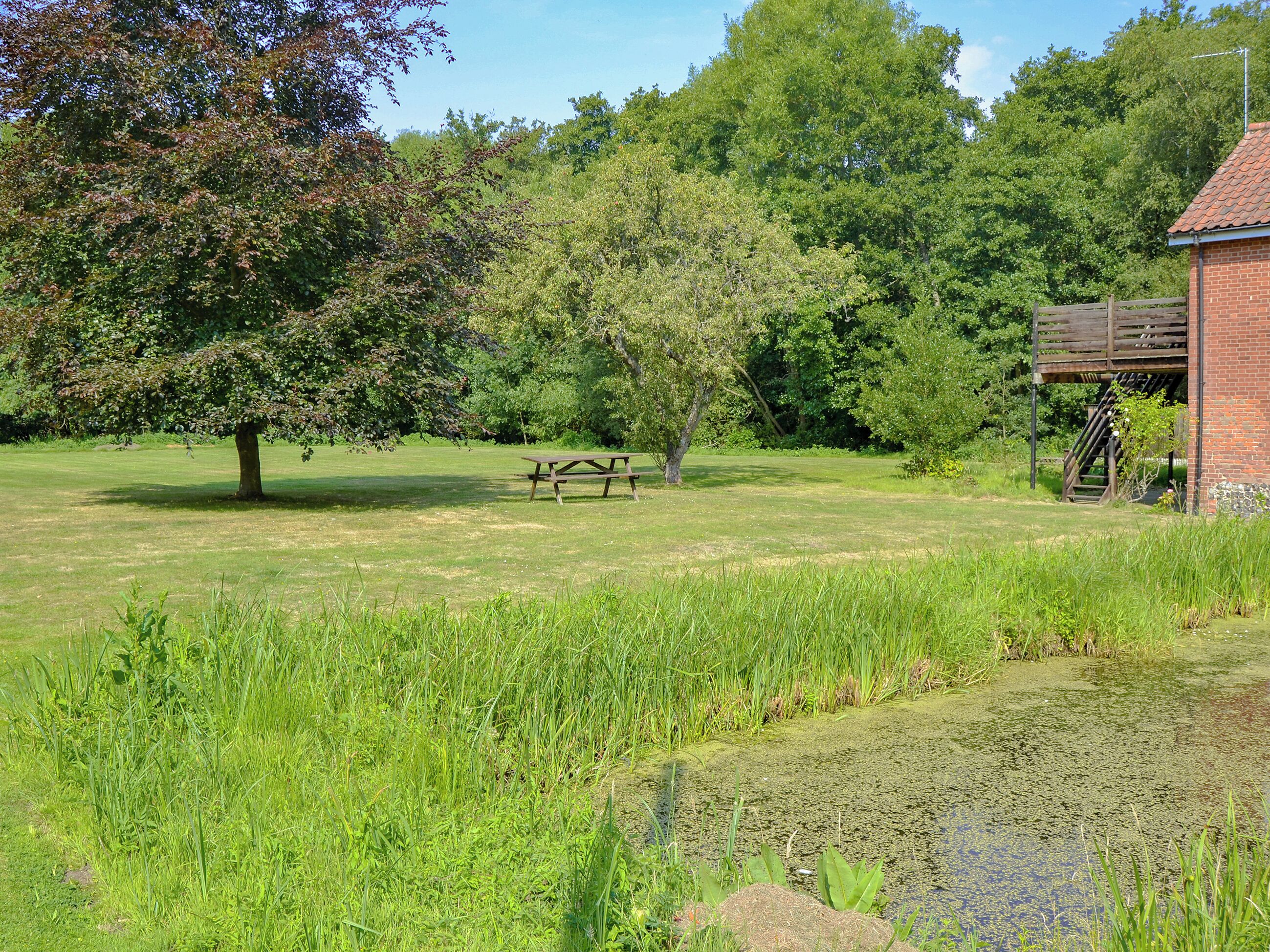 A grassy field with a picnic table and a brick building with a staircase.