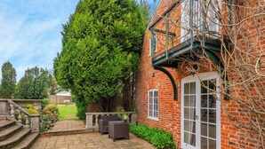 A brick house with a stone patio, a large tree, and a staircase leading to a balcony. - 6 bedroom accommodation in Fring, near Kings Lynn (Fring, near Kings Lynn)