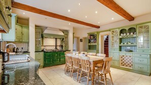 A spacious kitchen with green cabinetry, a granite countertop, and a dining area with wooden chairs. - 6 bedroom accommodation in Fring, near Kings Lynn (Fring, near Kings Lynn)
