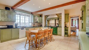 A spacious kitchen with a dining area, featuring green cabinets, wooden chairs, and a tiled floor. - 6 bedroom accommodation in Fring, near Kings Lynn (Fring, near Kings Lynn)