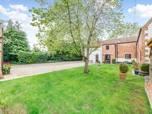 A brick house with a white exterior, a gravel driveway, and a well-maintained lawn. - 3 bedroom accommodation in York (York)