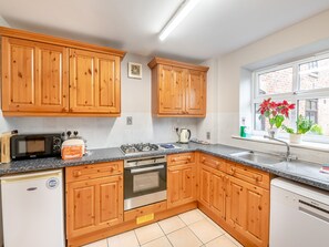 A kitchen with wooden cabinets, a microwave, a stove, and a sink. - 3 bedroom accommodation in York (York)