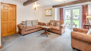 Ein gemütliches Wohnzimmer mit braunem Ledersofa, einem Holztisch und einer Holztür.