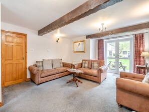 A cozy living room with a brown leather sofa, a wooden coffee table, and a wooden door.