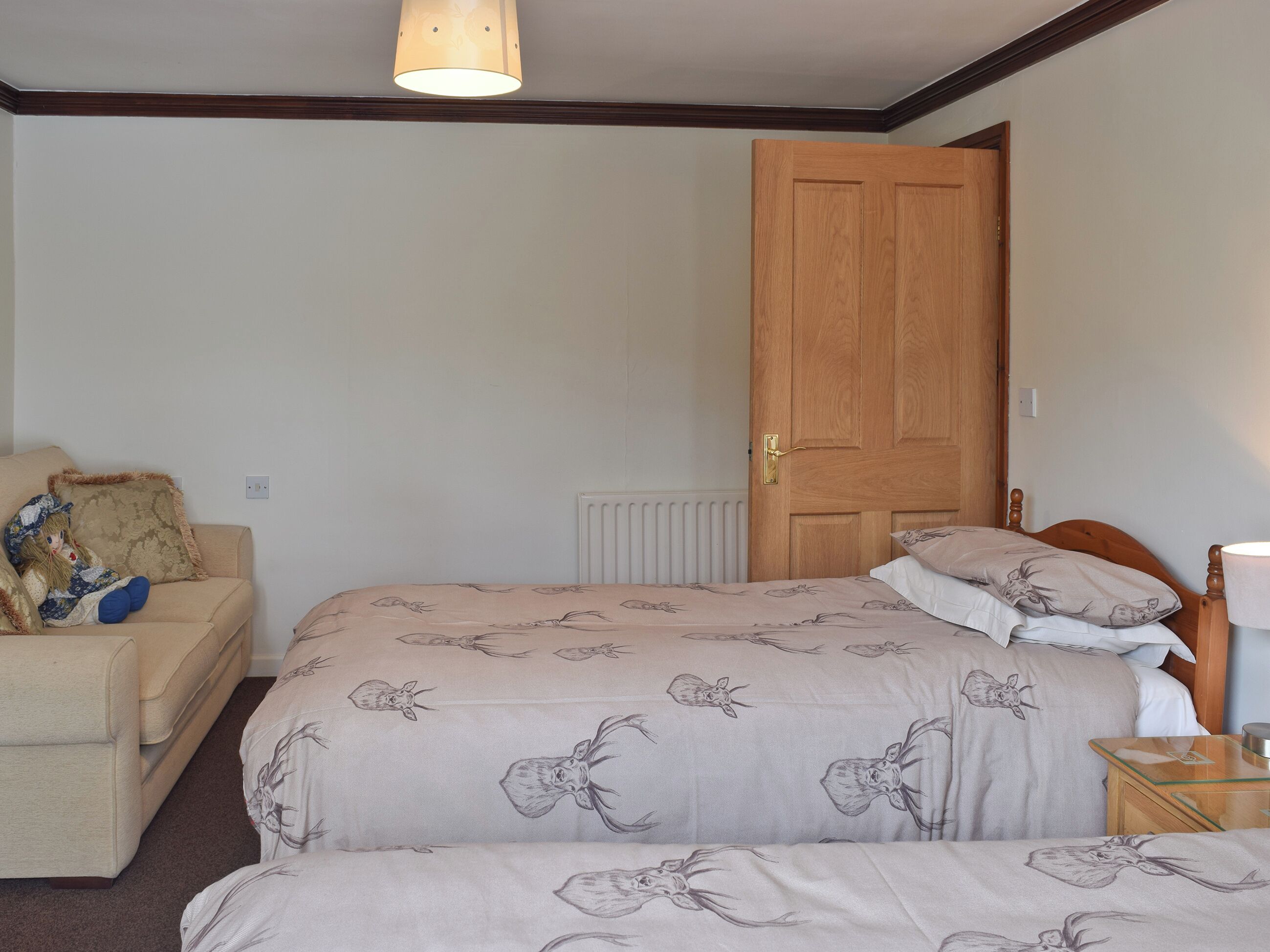 Een slaapkamer met een tweepersoonsbed, een houten deur, een radiator en een klein nachtkastje met een lamp.