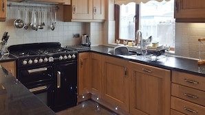 Une cuisine avec des meubles de rangement en bois, une cuisinière et une fenêtre donnant sur l’extérieur.