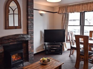 Una sala de estar con chimenea, un televisor de pantalla plana y un comedor con mesa y sillas.