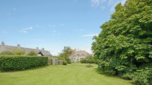 A well-maintained grassy lawn with stone walls and a large tree. - 7 bedroom accommodation in Acton, near Langton Matravers (Acton, near Langton Matravers)