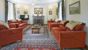 A living room with two sofas, a fireplace, a television, and a patterned rug. - 7 bedroom accommodation in Acton, near Langton Matravers (Acton, near Langton Matravers)