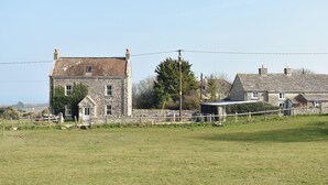 A stone house with a small porch and a fenced yard. - 7 bedroom accommodation in Acton, near Langton Matravers (Acton, near Langton Matravers)
