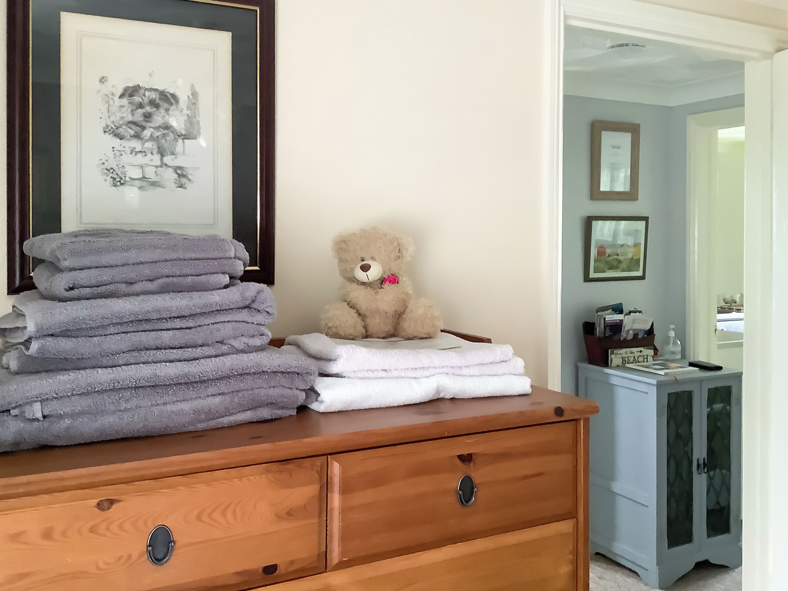 Een houten dressoir met opgevouwen handdoeken en een teddybeer.