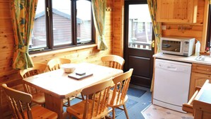 L’intérieur d’un chalet en bois comprend une table à manger, des chaises, un four à micro-ondes et un évier.