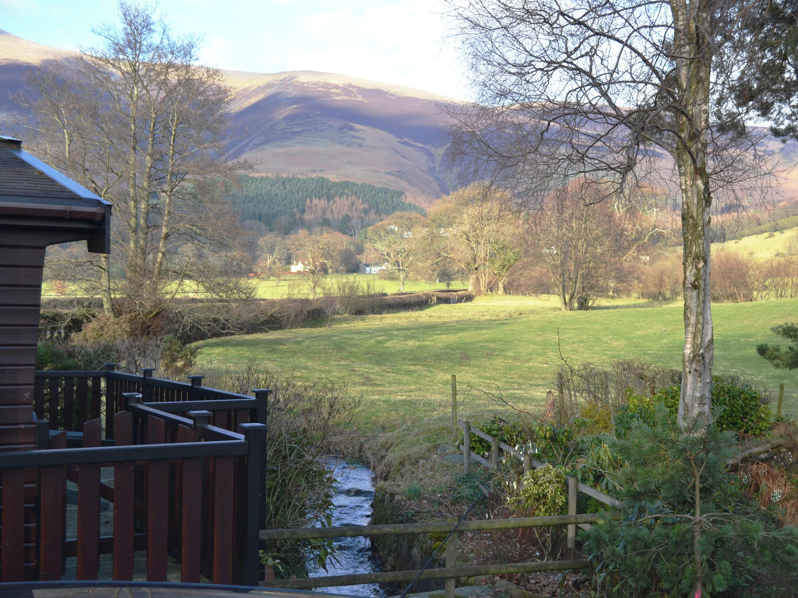 A wooden cabin with a deck overlooking a valley.