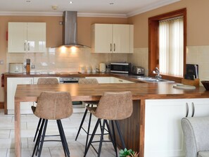 A modern kitchen with a central island, bar stools, and built-in appliances.