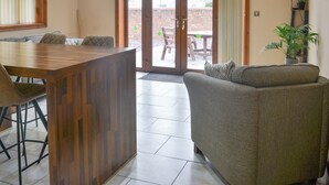 A living room with a sofa, a wooden coffee table, and a television mounted on the wall. - George's Gaff - E4432 (Near Skegness)