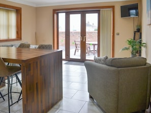 A living room with a sofa, a wooden coffee table, and a television mounted on the wall.