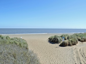 A sandy beach with dunes and a clear sky.