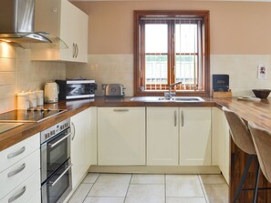 A kitchen with a stove, oven, toaster, and a window with blinds.