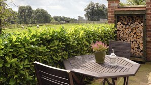 Eine Terrasse mit Tisch, Stühlen, einem Topfpflanzen und einer Laterne.