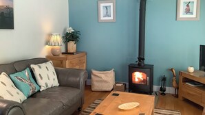 Ein gemütliches Wohnzimmer mit einer Couch, einem Tisch, einem Holzschrank, einer Wandheizung und gerahmten Bildern.