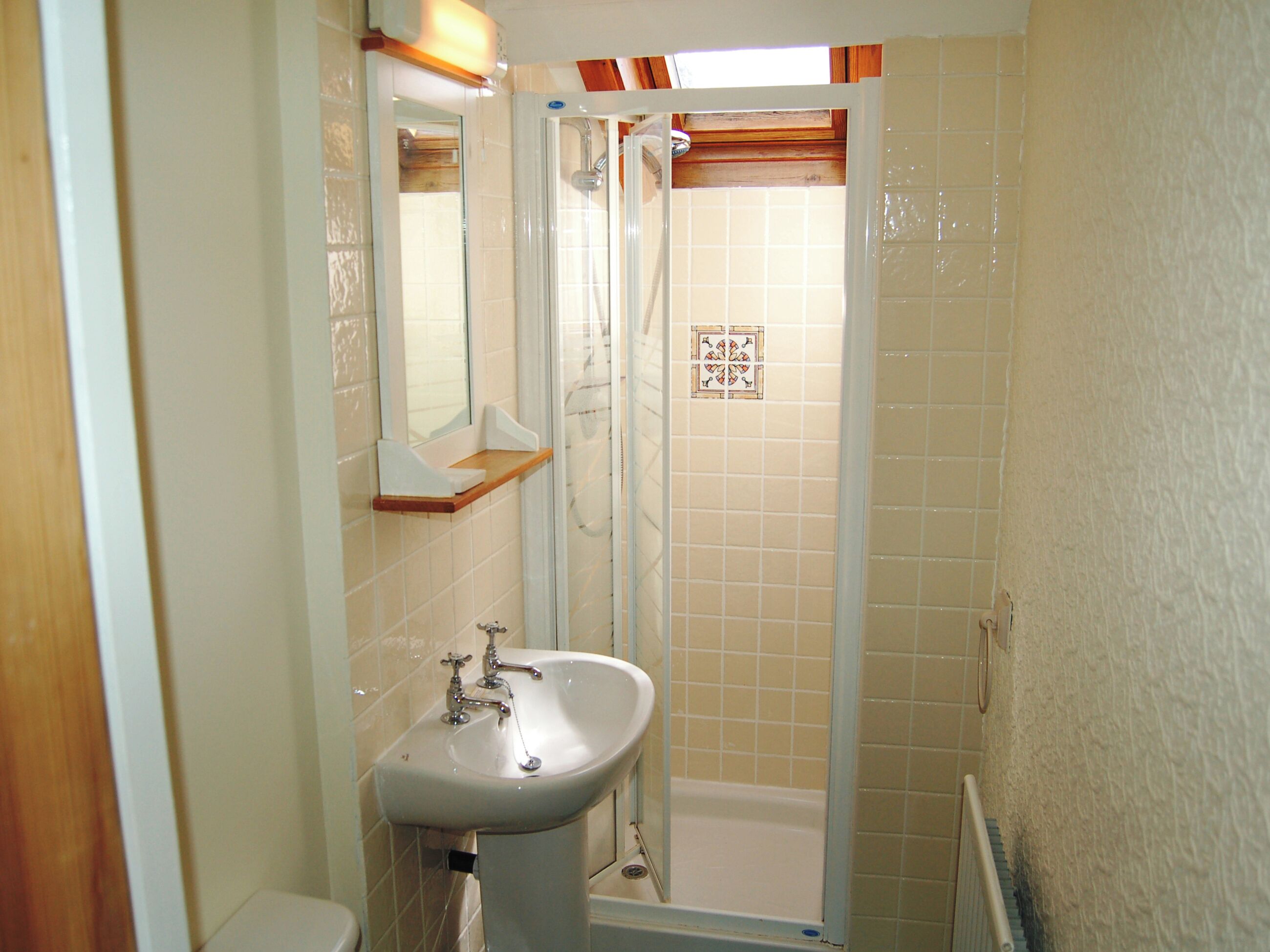 Un baño con lavamanos, espejo, ducha y paredes de azulejos.