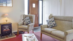 A living room with two armchairs, a small table with a glass bowl, a lamp, and a fireplace. - Carol's Cottage - E3043 (Wenhaston, near Southwold)