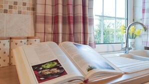 An open cookbook on a kitchen counter with a window and curtains in the background. - 2 bedroom accommodation in Cosheston near Pembroke (Cosheston near Pembroke)