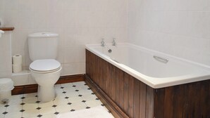 Une salle de bain équipée de toilettes, d’une baignoire et d’un porte-rouleau de papier toilette.