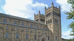 Un bâtiment historique doté d’une grande tour centrale et d’une façade symétrique ornée de fenêtres en arc.