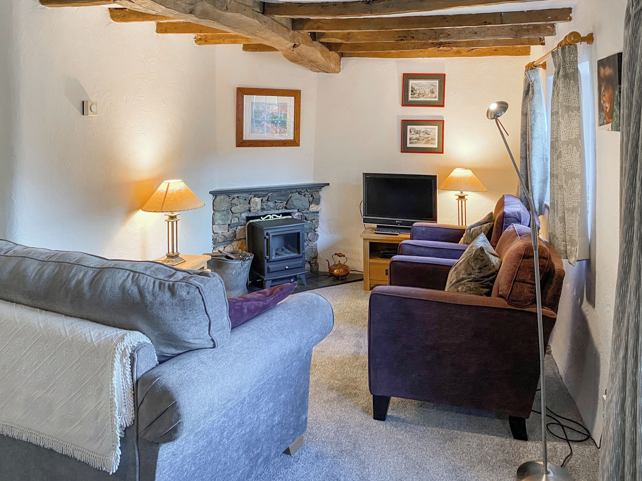 A living room with a stone fireplace, a television, and a sofa.