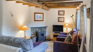 Ein Wohnzimmer mit Kamin aus Stein, einem Fernseher und einem Sofa.