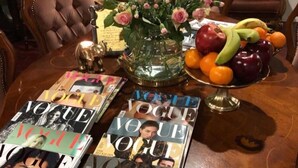 A dining table with magazines, a vase with flowers, and a fruit bowl. - Wherever Boutique Hostel (Rovaniemi)