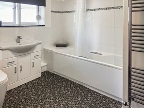 Un baño con lavabo, espejo, inodoro y bañera.