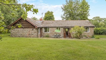 A stone cottage with a tiled roof, a wooden porch, and a small garden.
